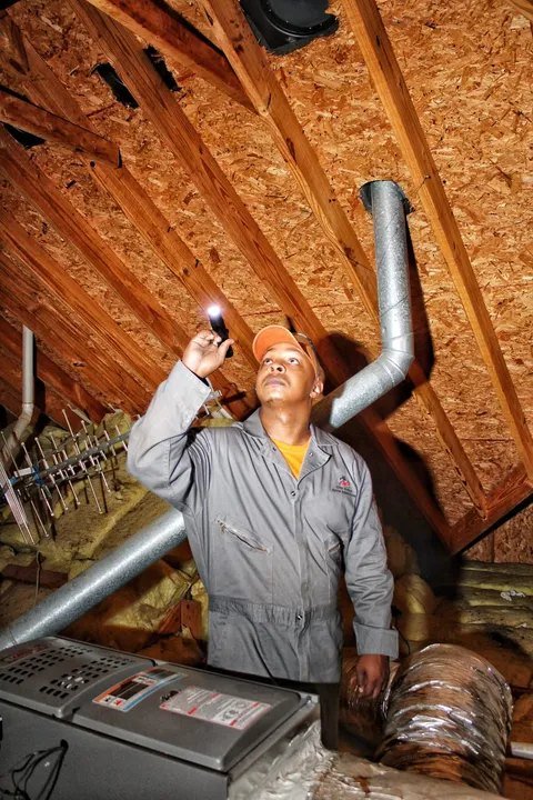 Client supplied photo of an inspector examining a home attic